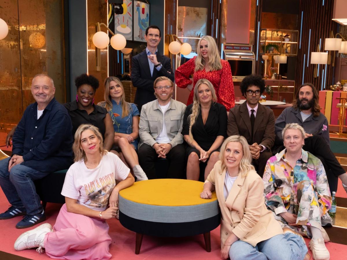 A group of comedians pose on a TV show set.