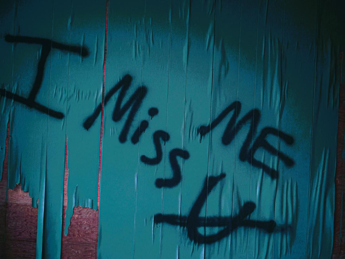 Graffiti reads 'I miss me' with u crossed out under the 'mem'