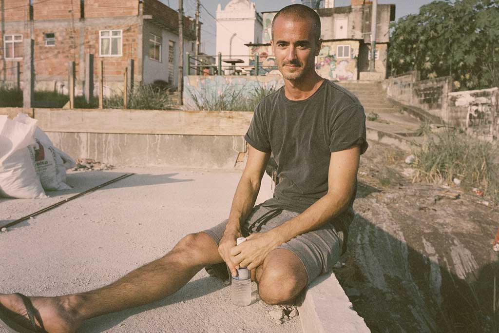 A man sits on a concrete path with one leg splayed out in front.