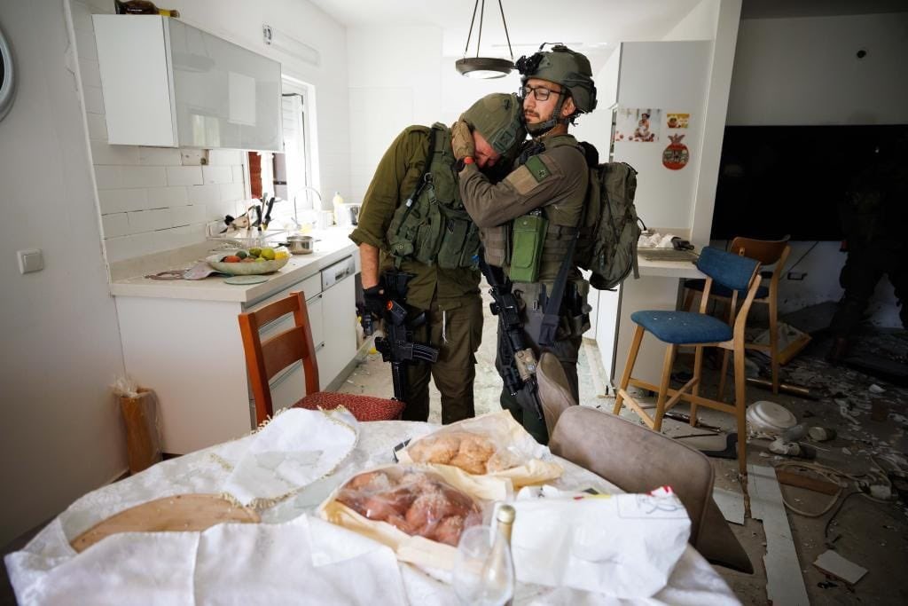 Two soliders console each other as they search a house that has been ransacked.