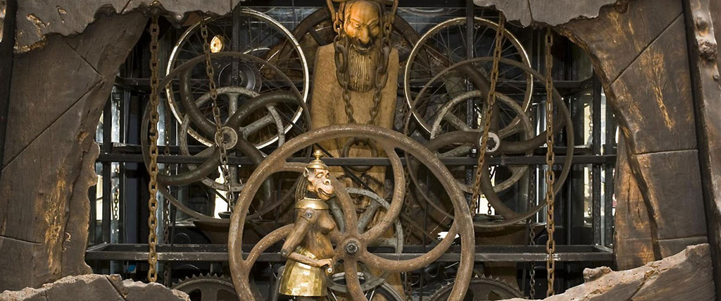 A close-up of a complex clock mechanism featuring small statues within it.
