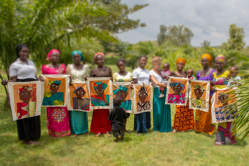 A group of Nigerian women hold up self-portraits they have painted.