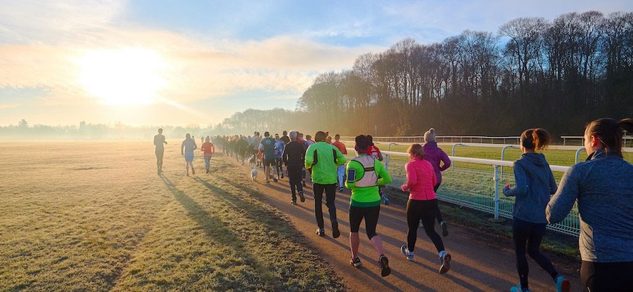 Runners jog along a path into the sunset.