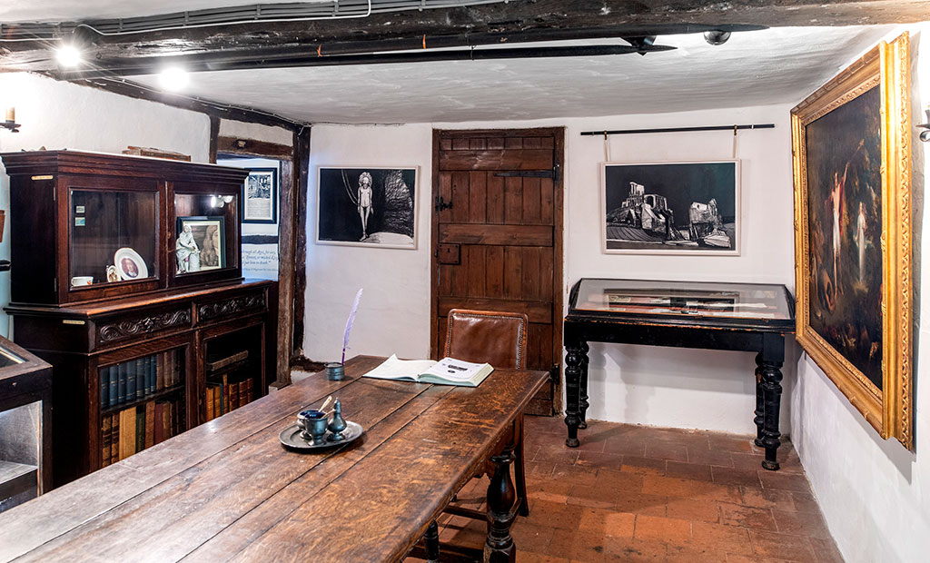 Inside a history cottage, black and white illustrations hang on the wall.
