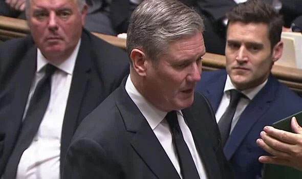 Keir Starmer stands in the House of Commons and recites an oath from a card held up in front of him.