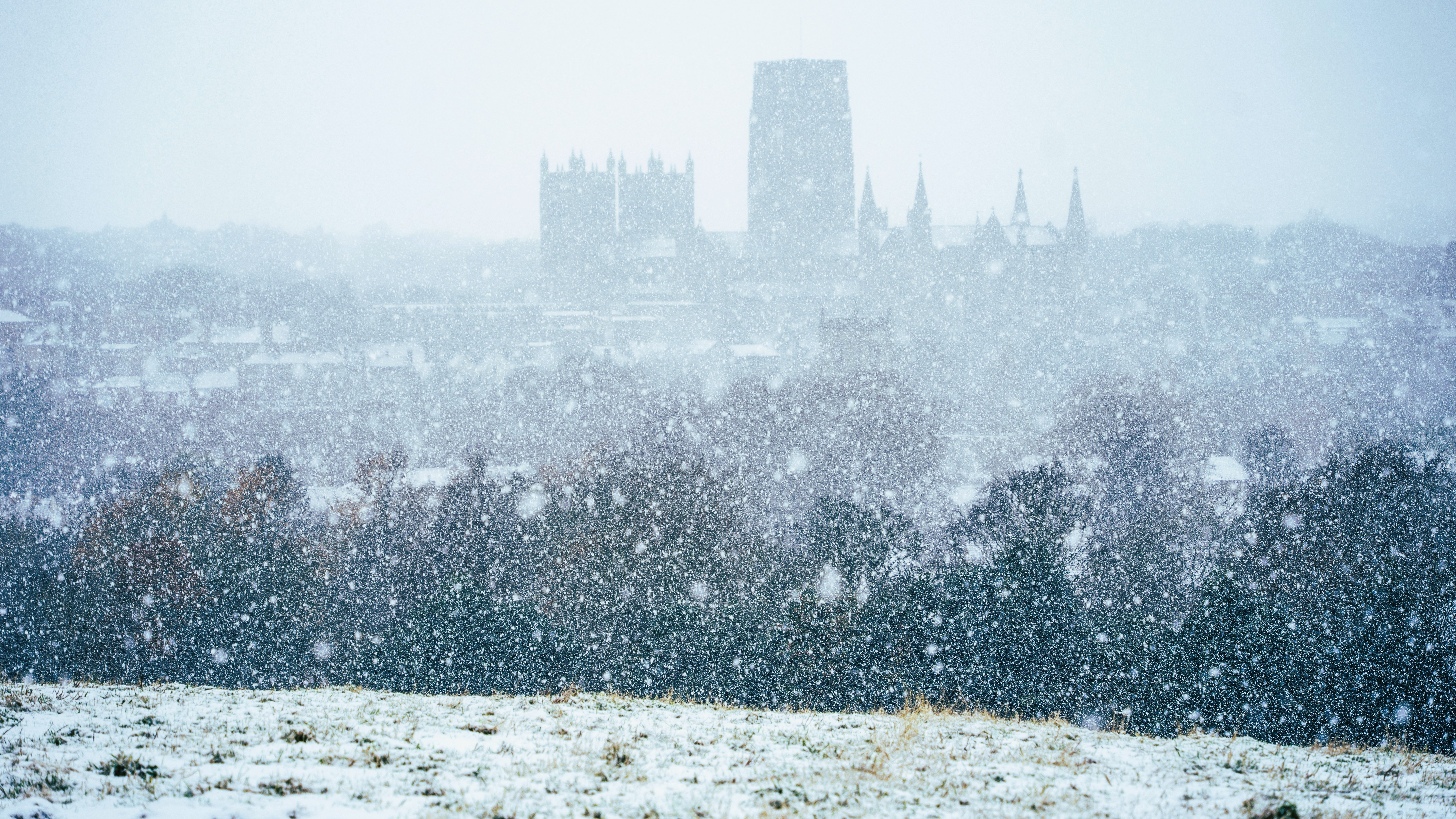 Snow falling pixilates the view from a hill towards Durham Cathedral.