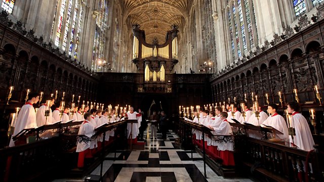 Choristers stand and sing in choir stalls in a church