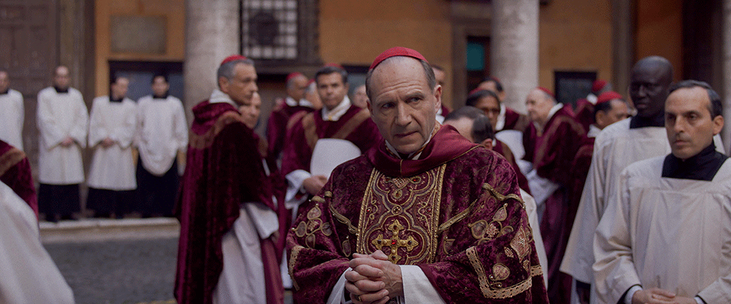 A cardinal glances to the side as he stands amid a gather of clergy,