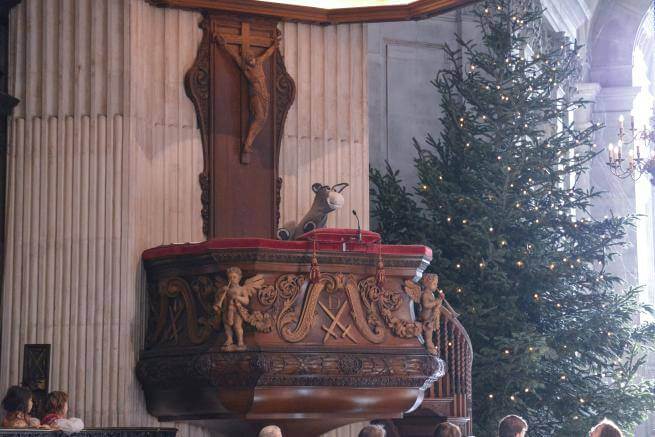 A puppet donkey peaks over the edge of a cathedral pulpit