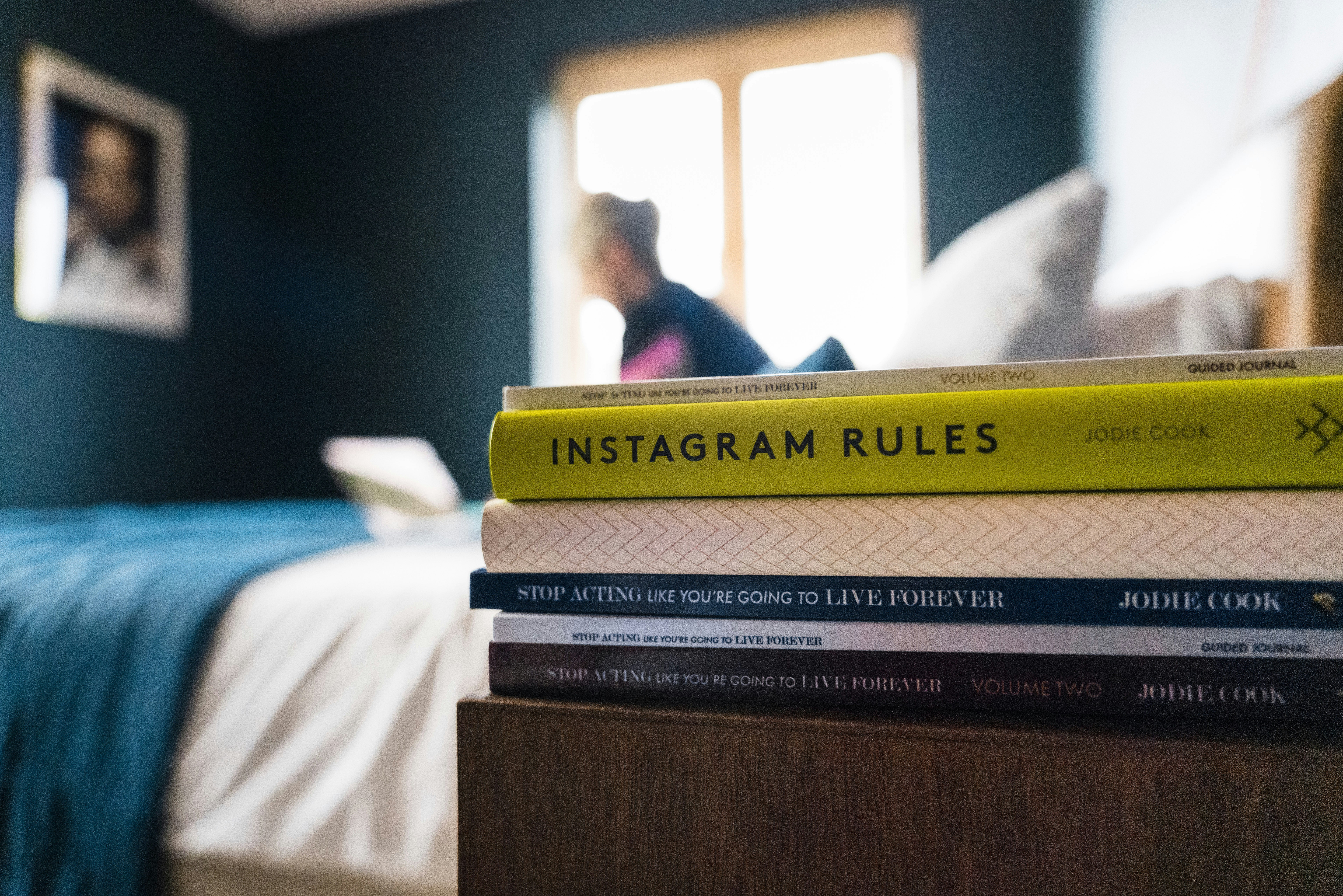 A pile of books on a bedside table.