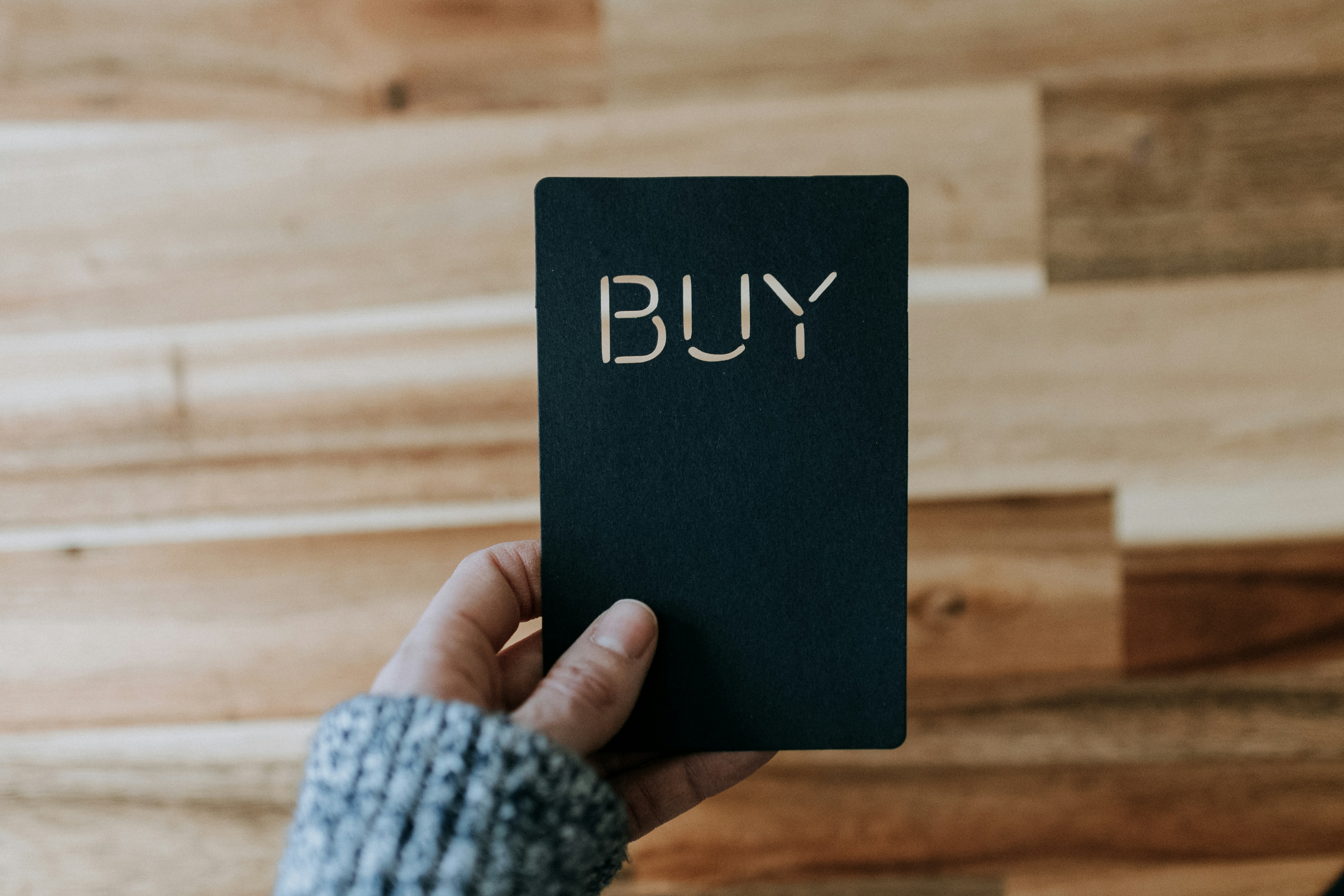 a hand hold a black payment card that reads 'buy'.