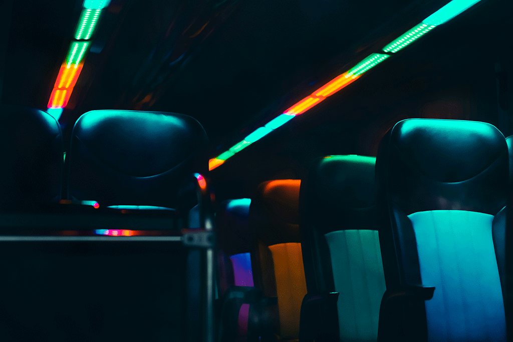 Empty bus seats are lit in dark neon colours.