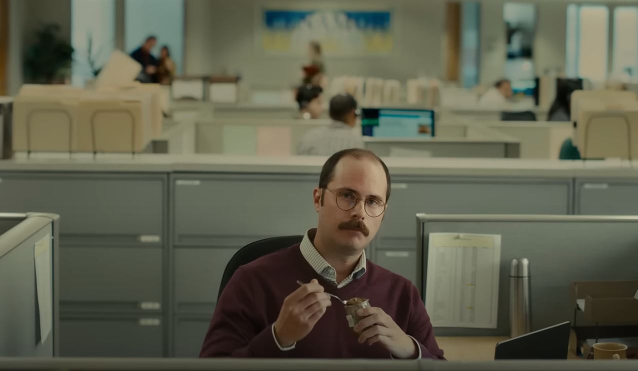 A worker at a desk sits back contemplating a situation