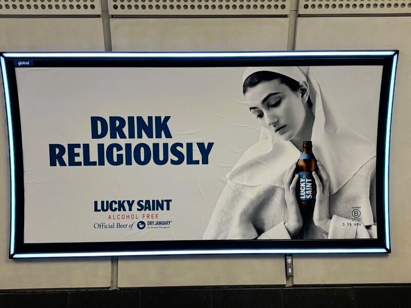 A subway billboard ad show a nun cradling a beer.