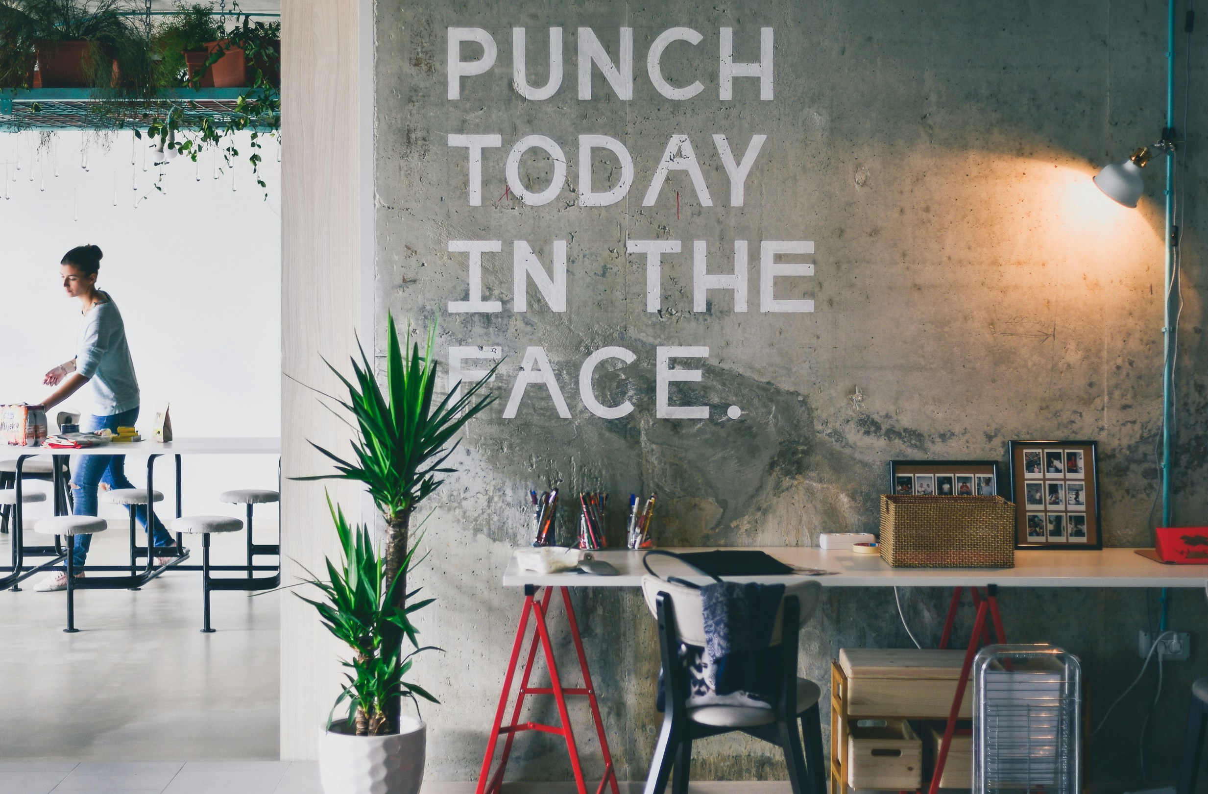 An office wall displays a huge motto reading 'punch today in the face'