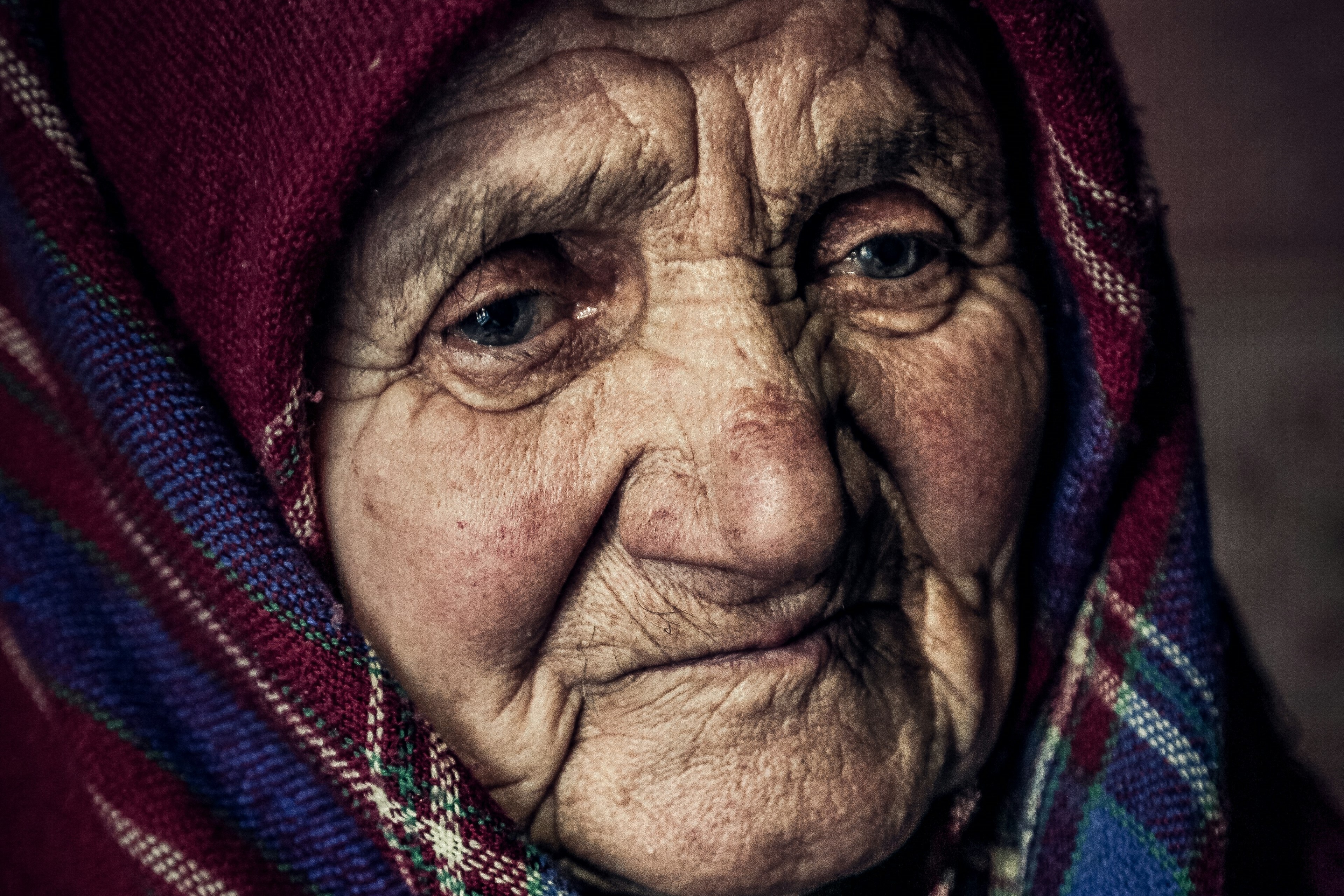 An old woman wearing a shawl looks pensive.