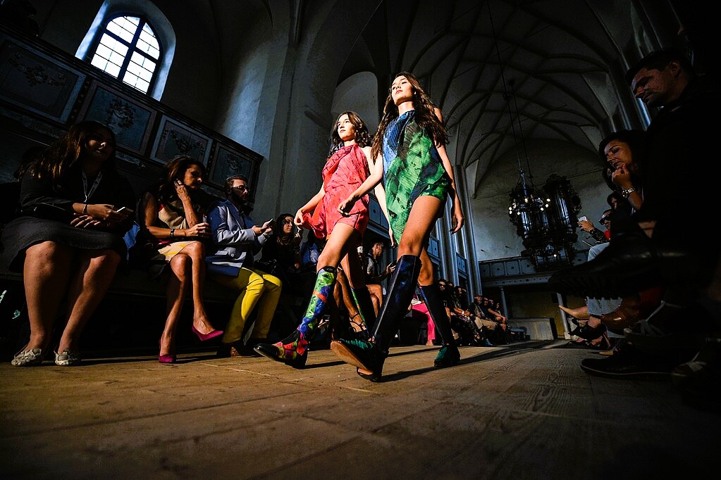 Two models stride along a catwalk of a fashion show held in a church