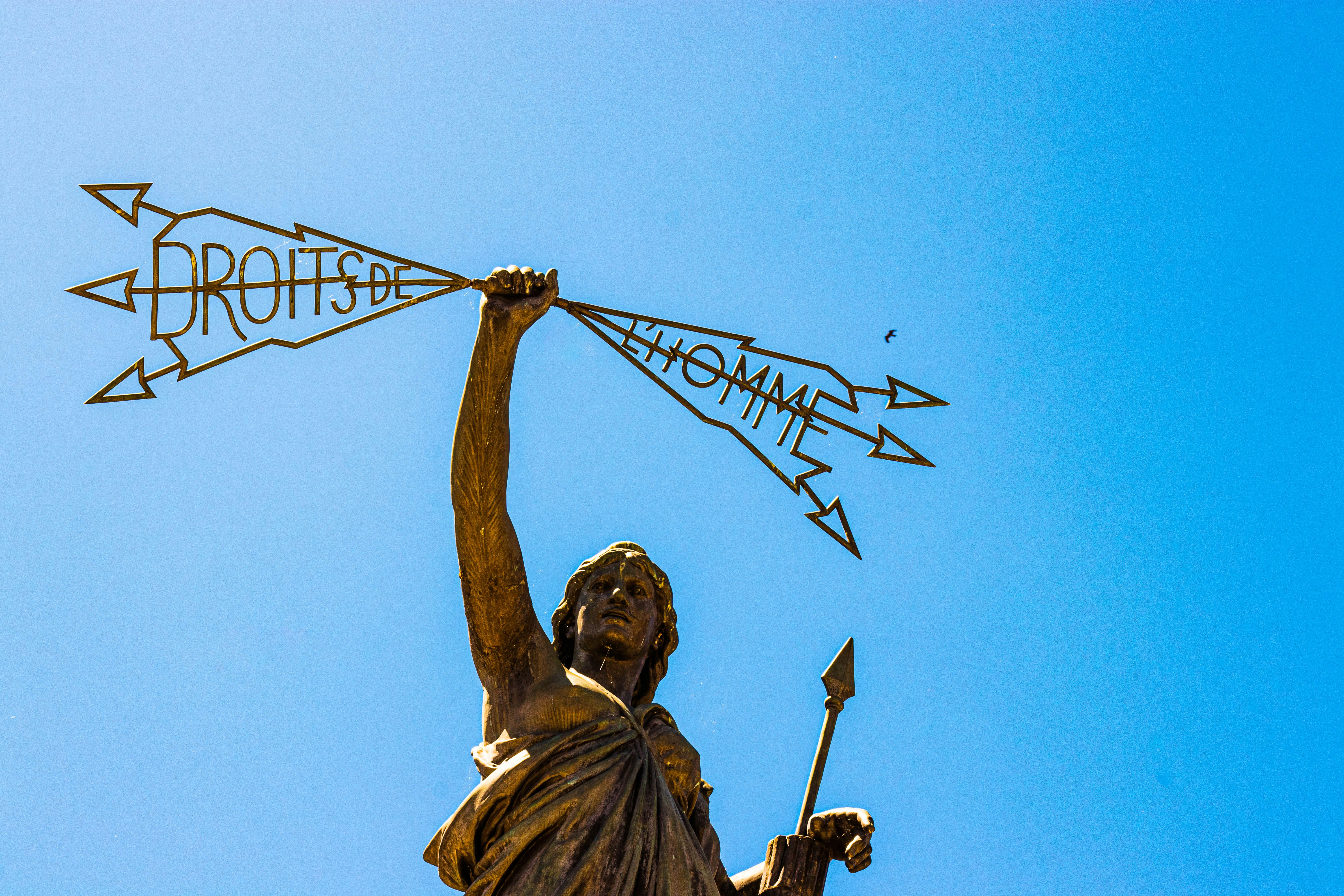 A statue of a woman holding a spear in one hand a lightening bolt in the others that reads: 'Droits de  l'homme'.