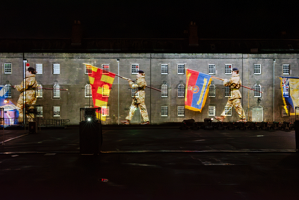 A projection of soldiers marching and carrying flags.