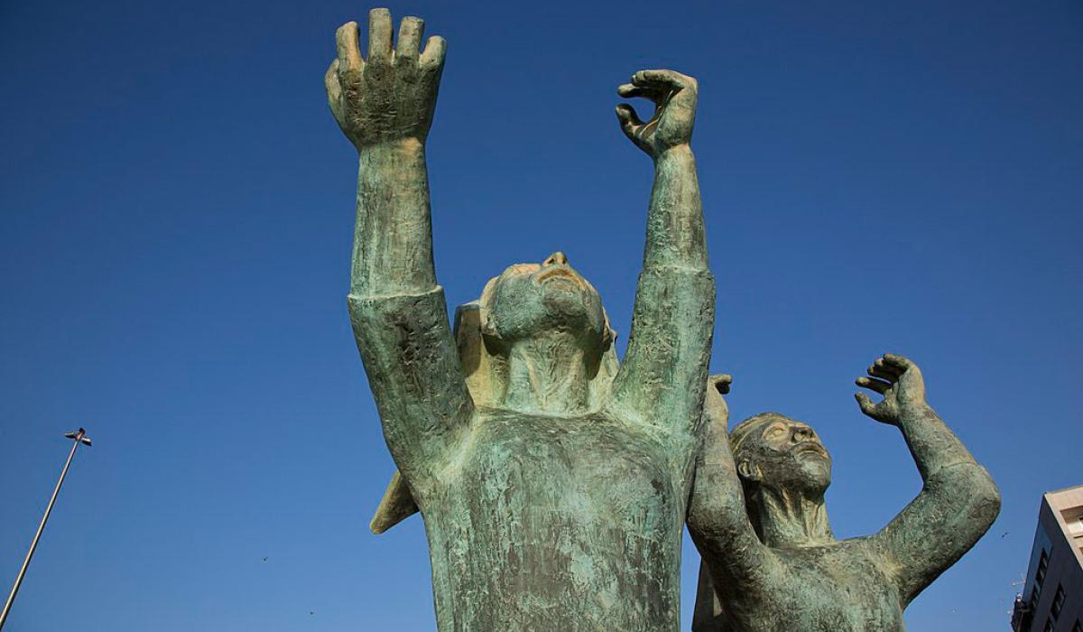 A sculpture shows mourning women raising hands and fists to the sky.