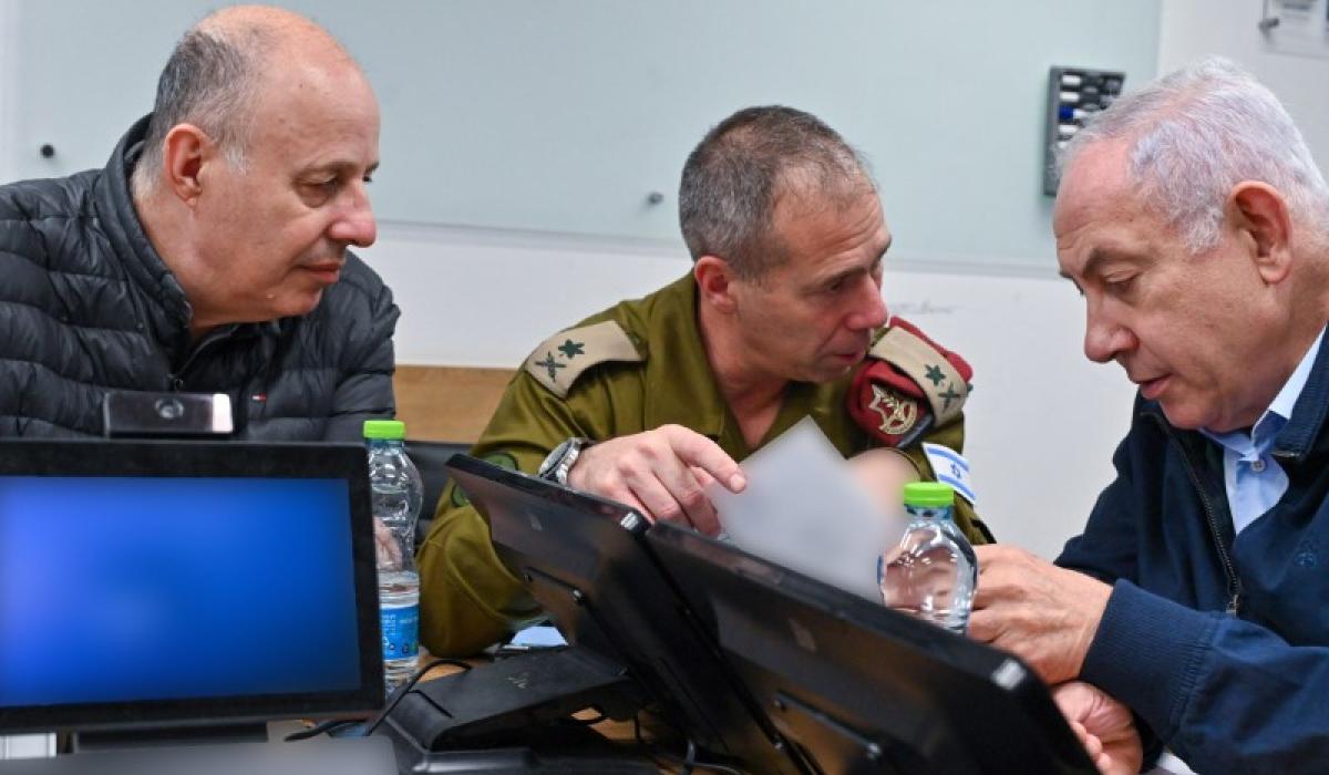 Three men huddle around a laptop and talk animatedly.