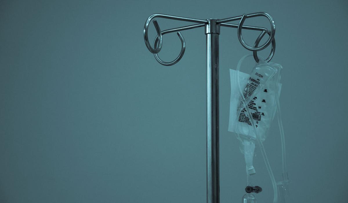 A IV drip bag hangs from a medical stand.