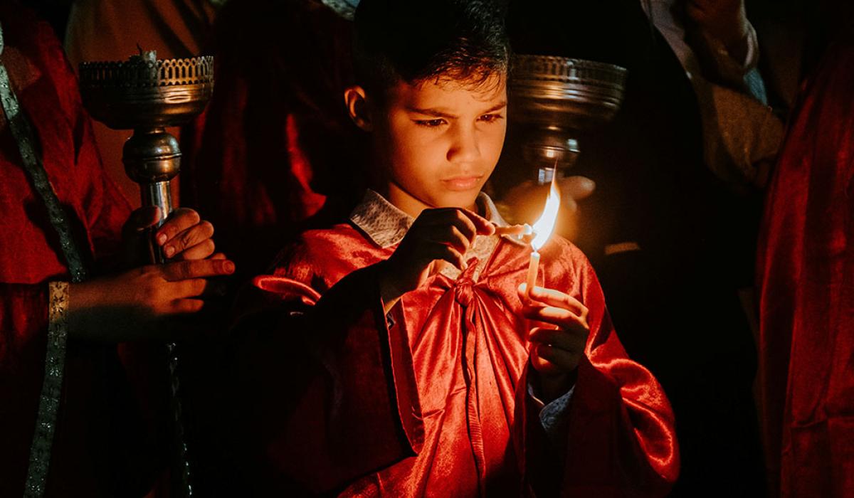 A boy concentrates hard as he holds one candle to another to light it.