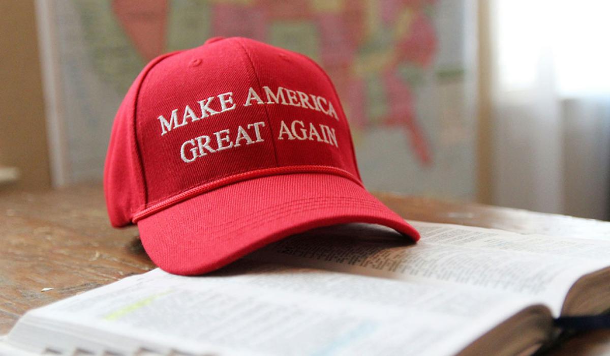 A red baseball cap, with Make America Great Again written across it, sits on an open bible.