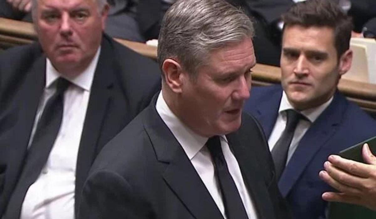 Keir Starmer stands in the House of Commons and recites an oath from a card held up in front of him.