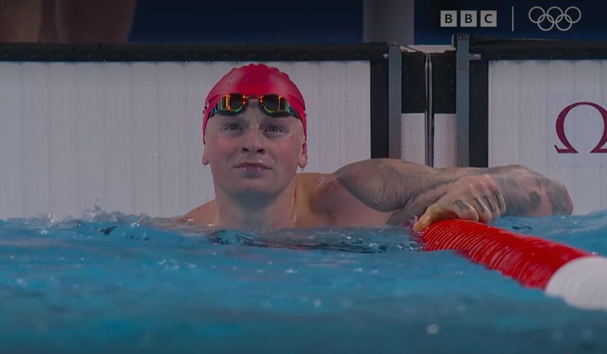 A swimmer at the end of a race, looks to the result screen.