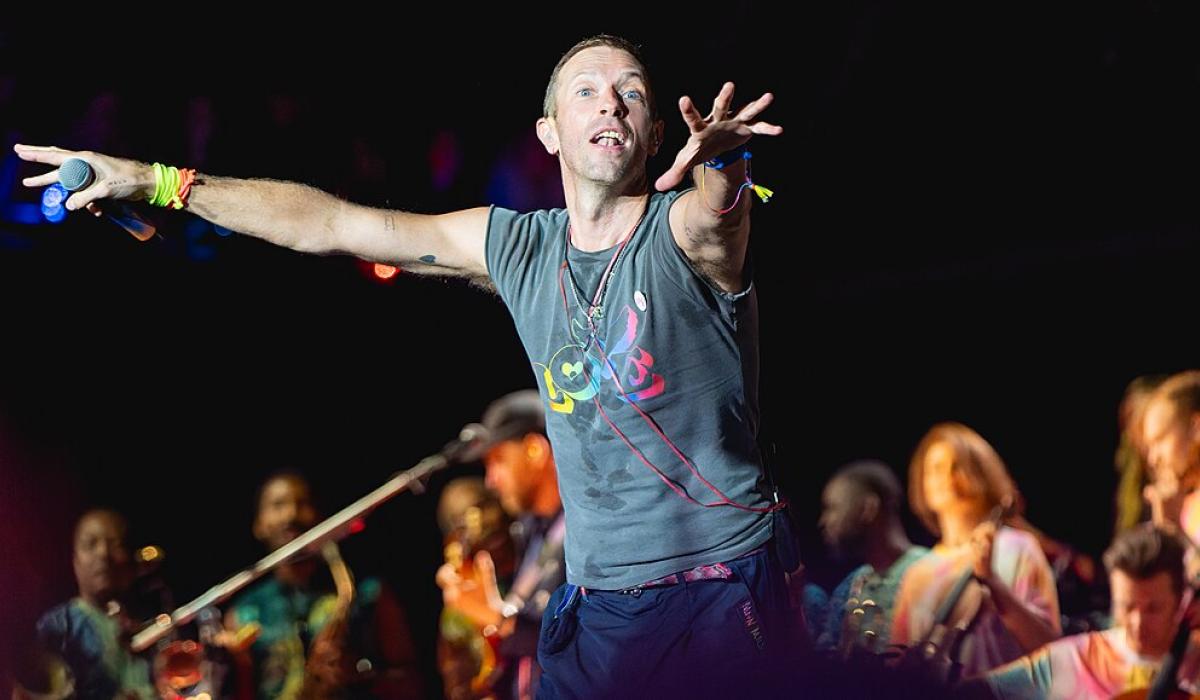 A singer on a stage holds out his arms to conduct the crowd.