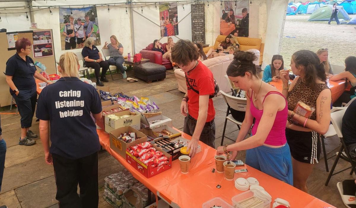 Festival goers, in a cafe tent, make drinks or sit around talking