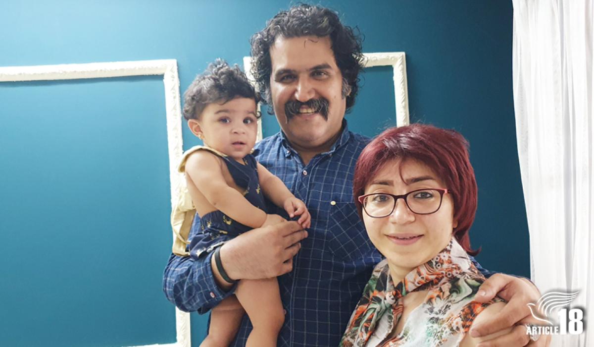 A toddler is held by her father while he stands next to her mother.