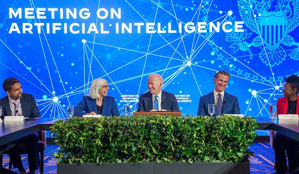 A board of experts sit at a table against a conference backdrop.