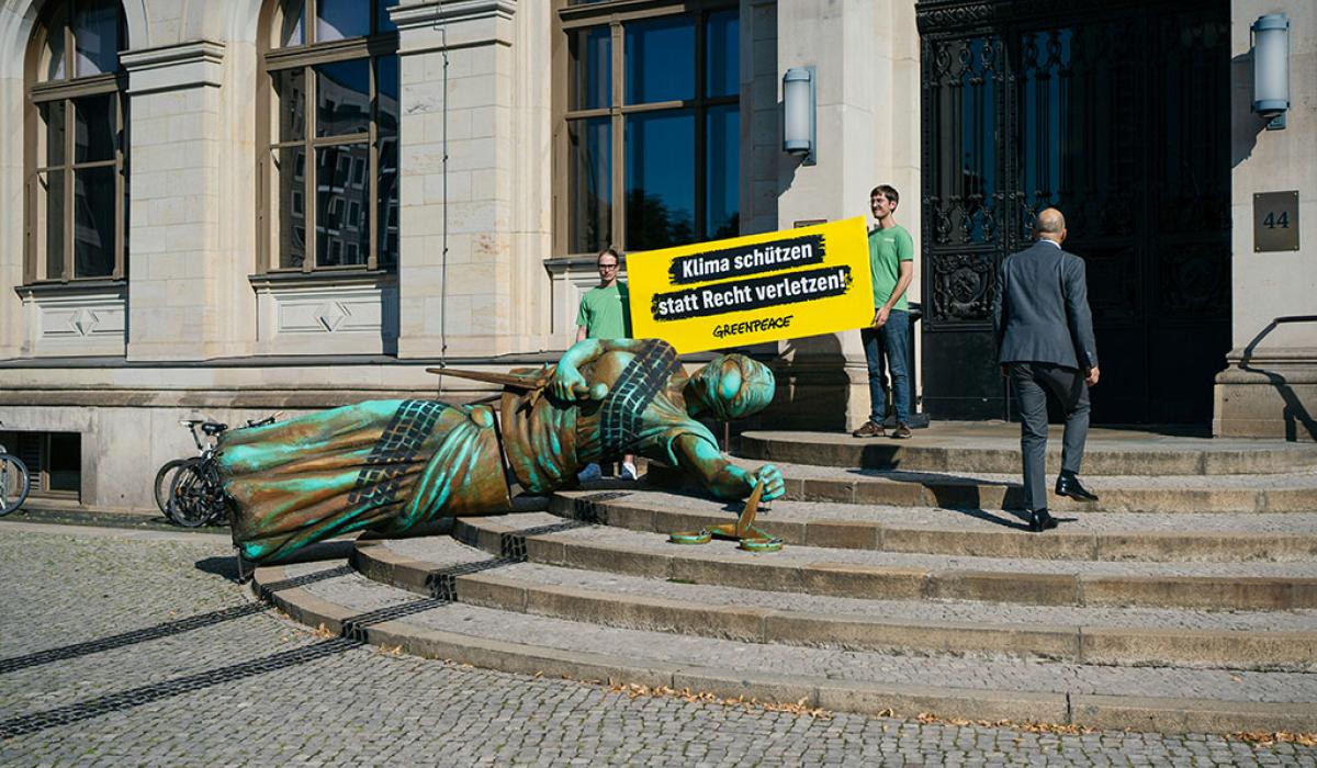 A fallen statute with tyre tracks over it lies on the steps to a government building, in a form of protest.