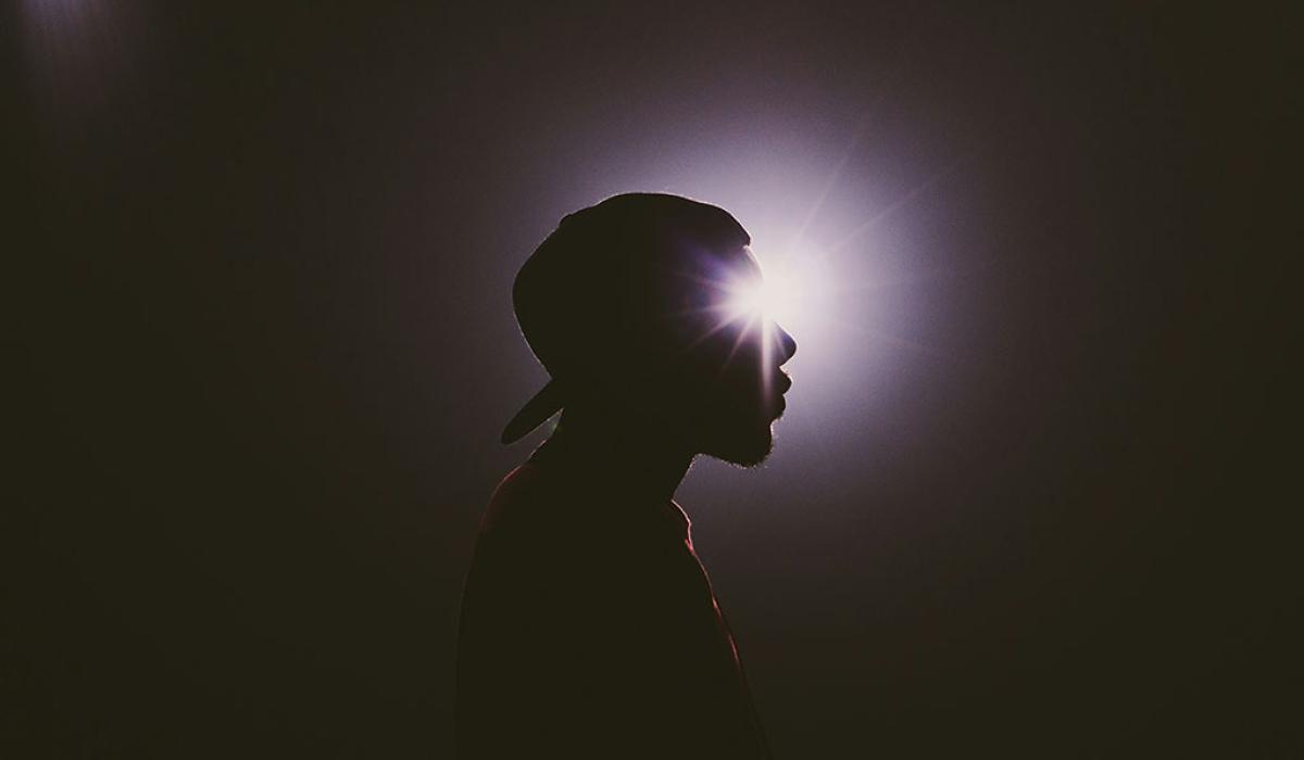 A star burst of light appears to emanate from the eye of a man's head in silhouette. 