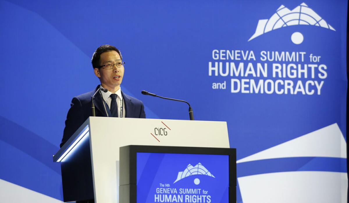 A conference speaker at a podium against a backdrop of blue.