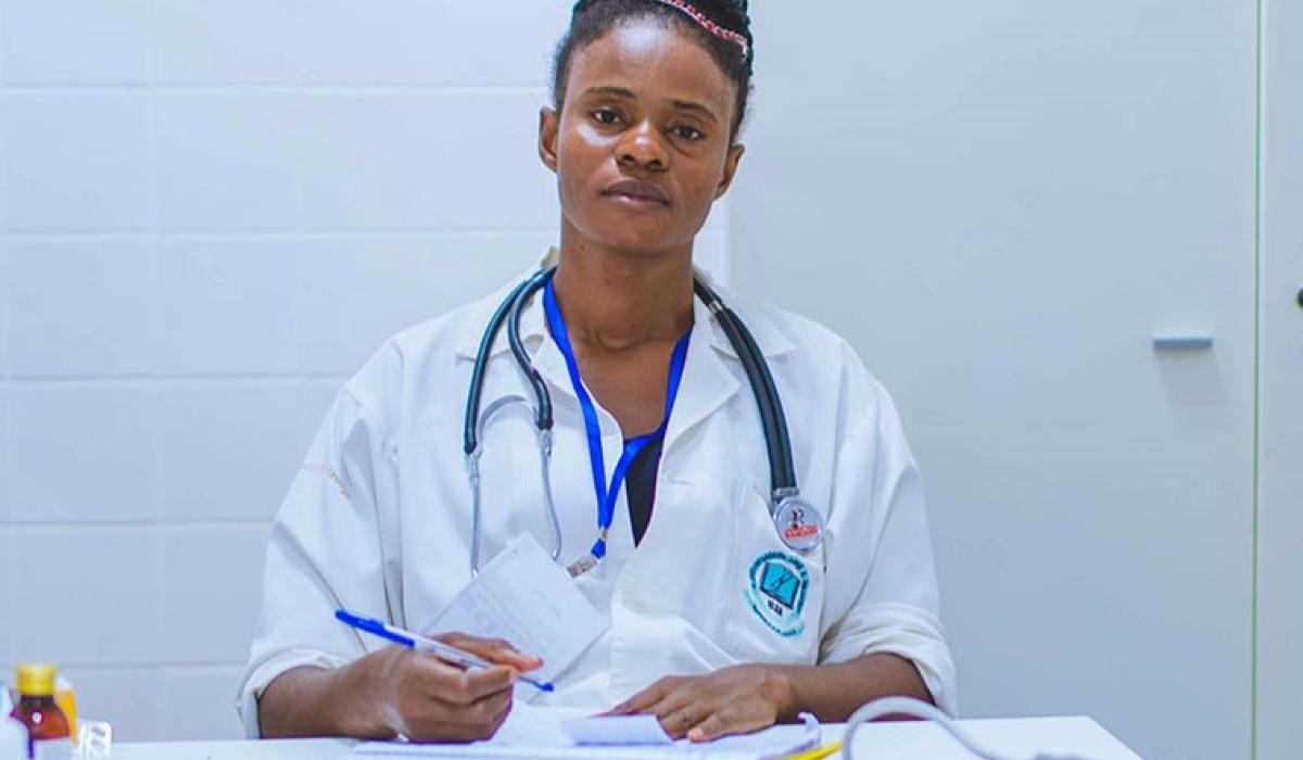 A tired-looking doctor sits at a desk dealing with paperwork.