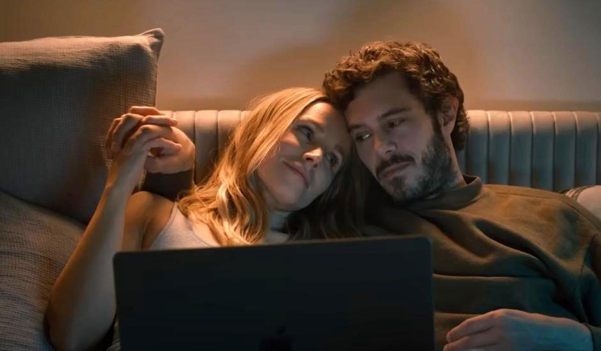 A couple together on a sofa watch a laptop,