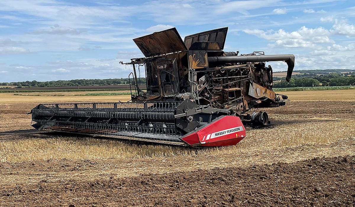 A soot stained burnt-out harvester sits in a recently harvested field.