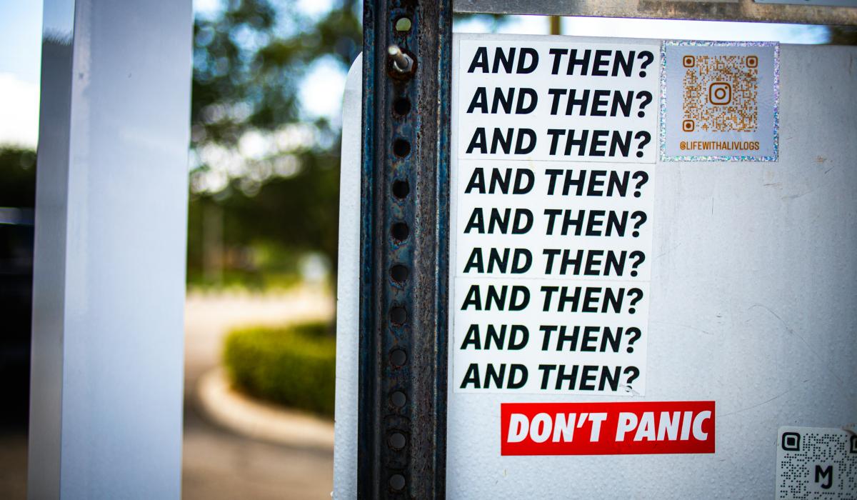 A street sticker displays multiple lines reading 'and then?'