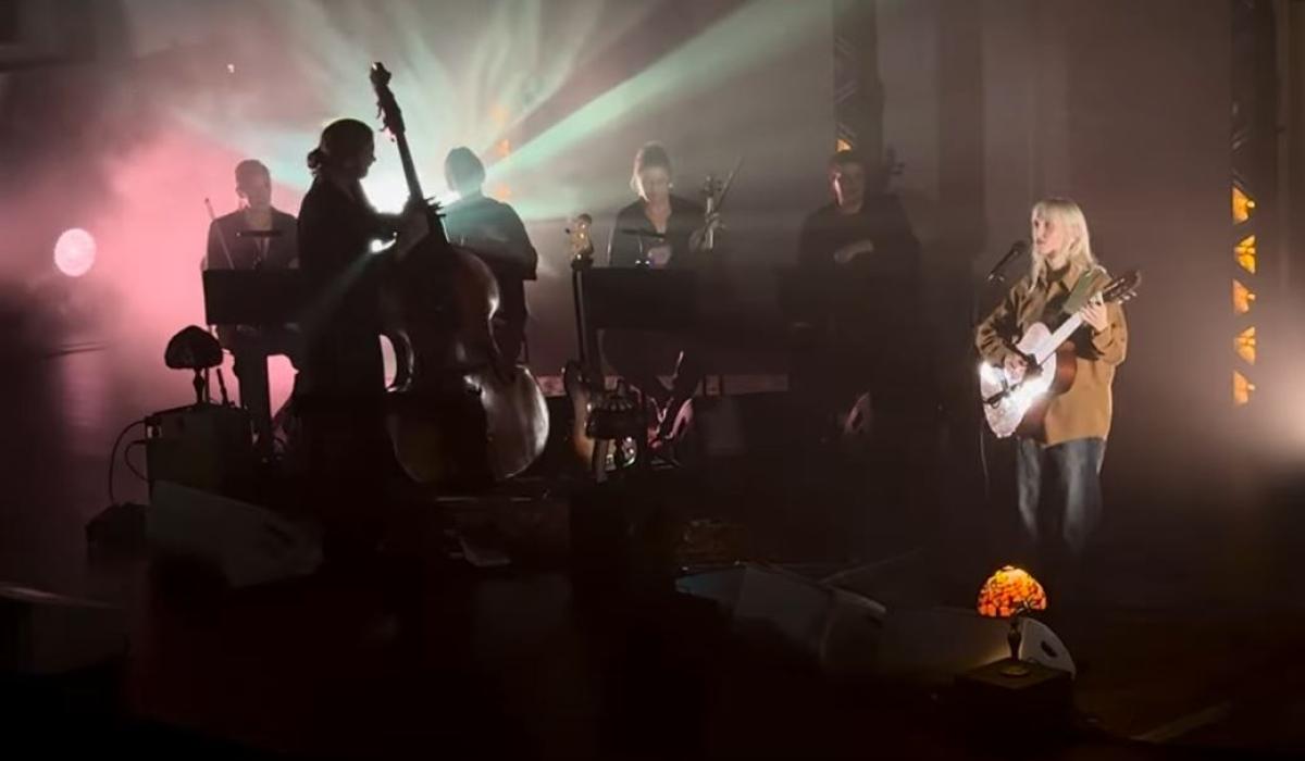 A misty back lit stage hosts a singing guitarist and a double base player