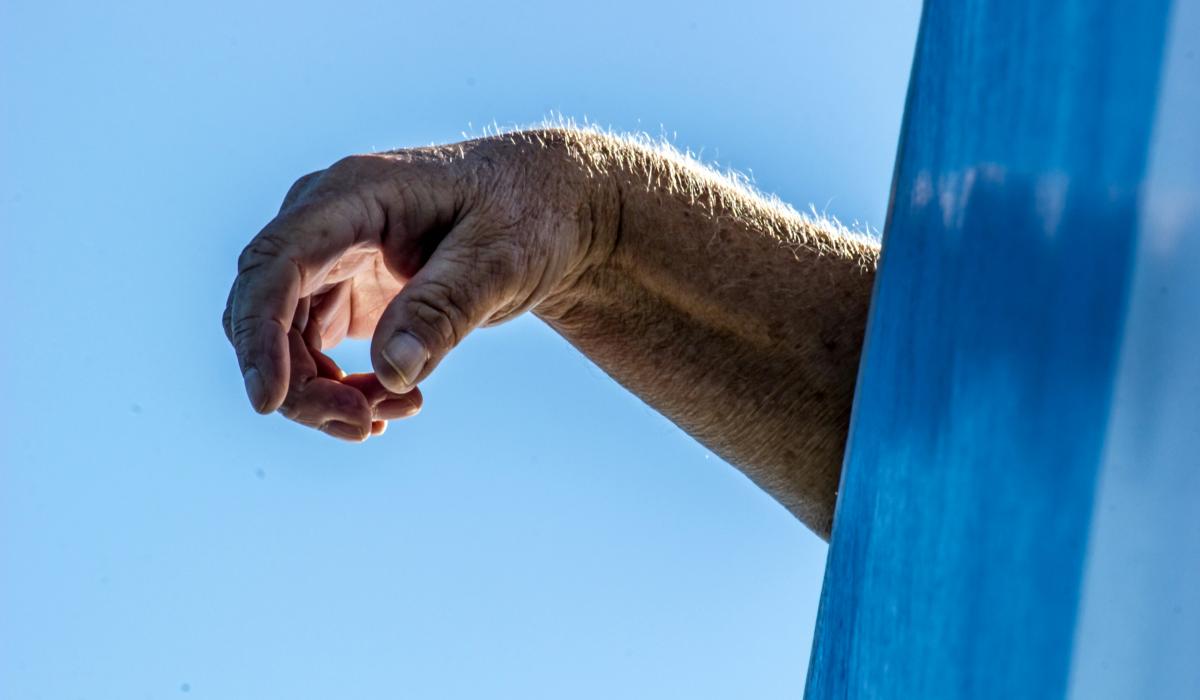 A hand drapes over the side of an object out of shot.