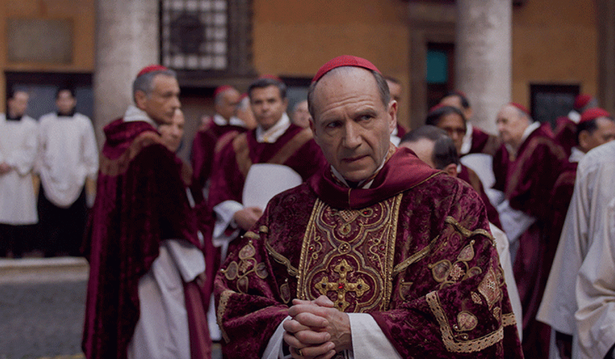 A cardinal glances to the side as he stands amid a gather of clergy,