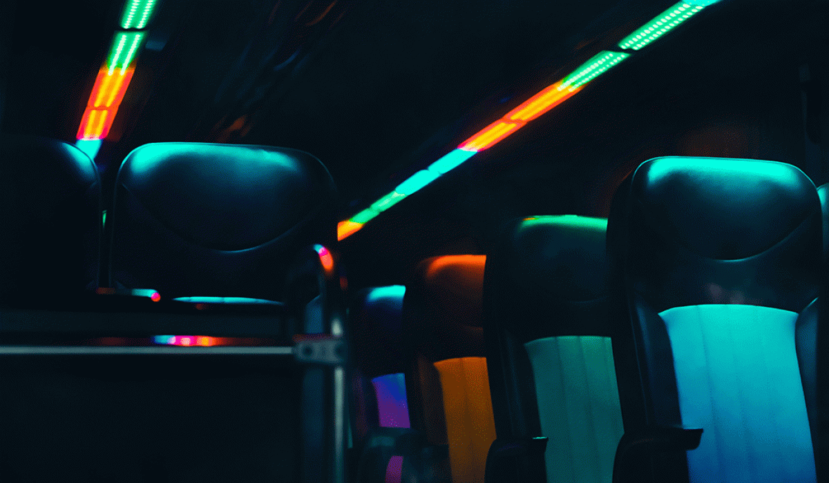 Empty bus seats are lit in dark neon colours.