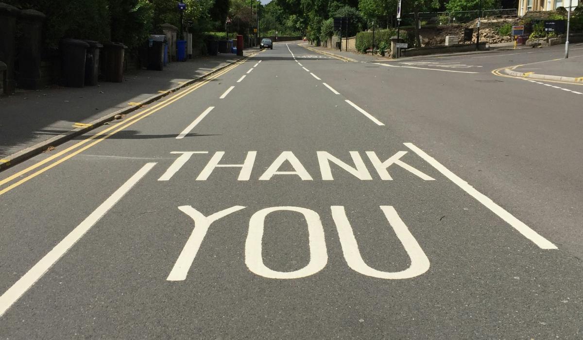 A  painted sign on a road reads 'THANK YOU'