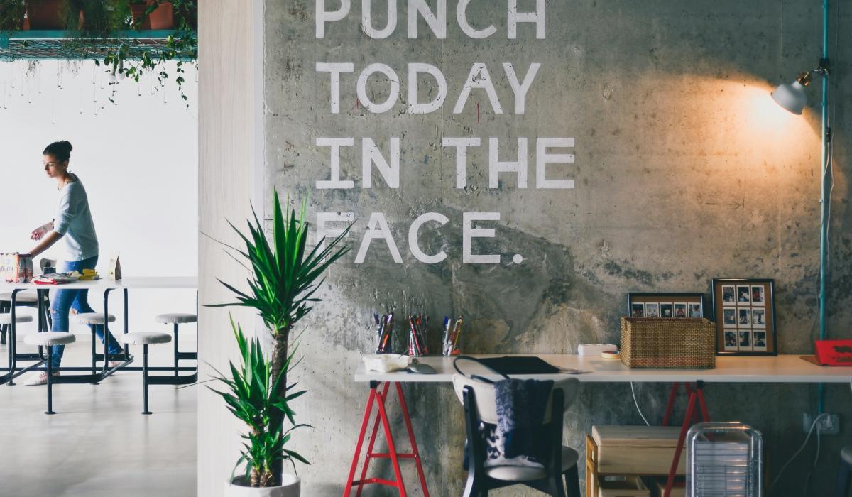 An office wall displays a huge motto reading 'punch today in the face'