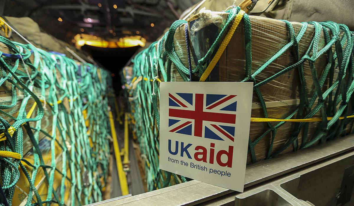 Cargo sits in nets inside a plane, a sign reads 'UK Aid'