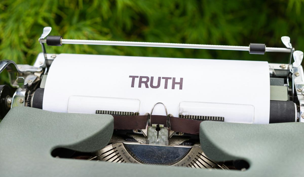 A typewriter holds a piece or paper reading 'truth'