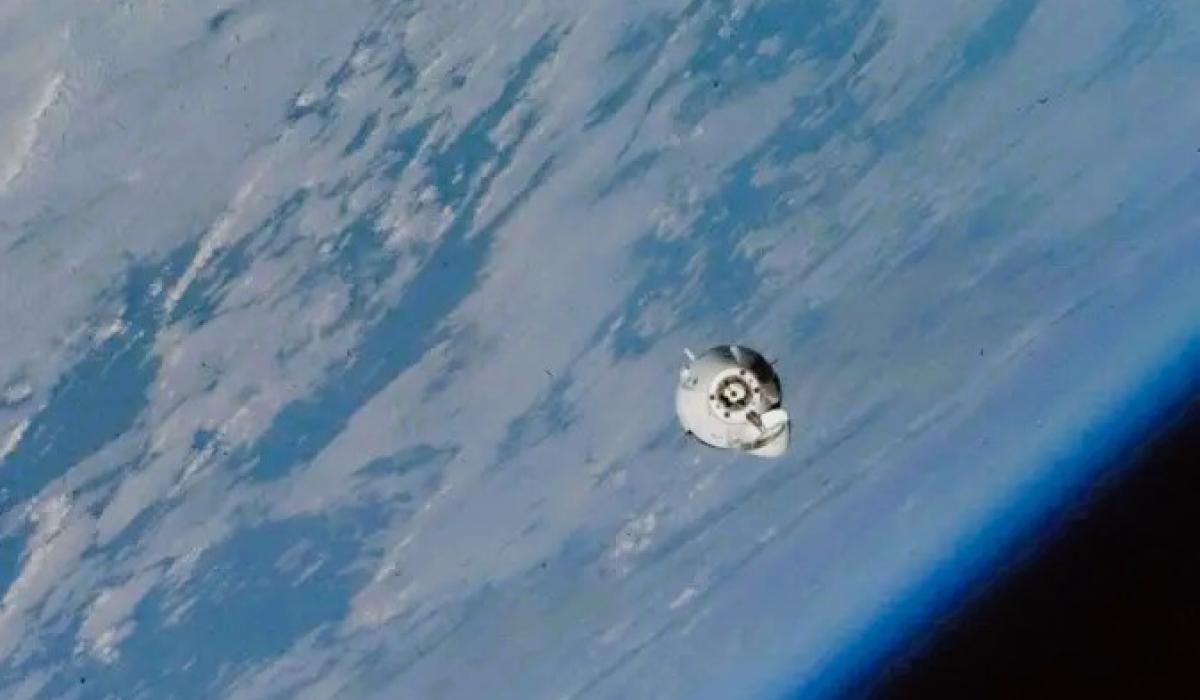 A small white space capsule orbits around the earth.